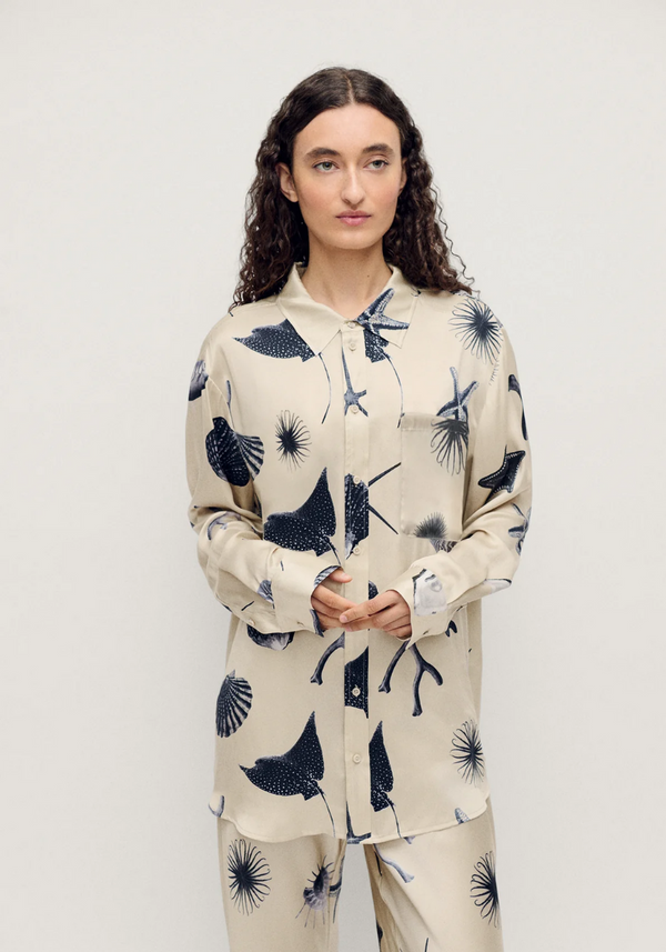 Person wearing a cream-colored pajama set with black abstract patterns on a white background