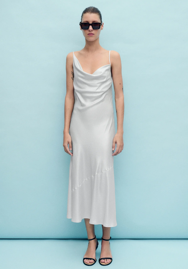 Woman wearing a white slip dress against a light blue background