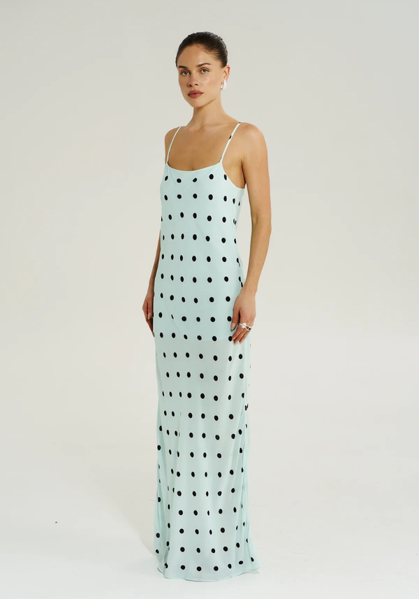 Woman wearing a light blue dress with black polka dots on a white background