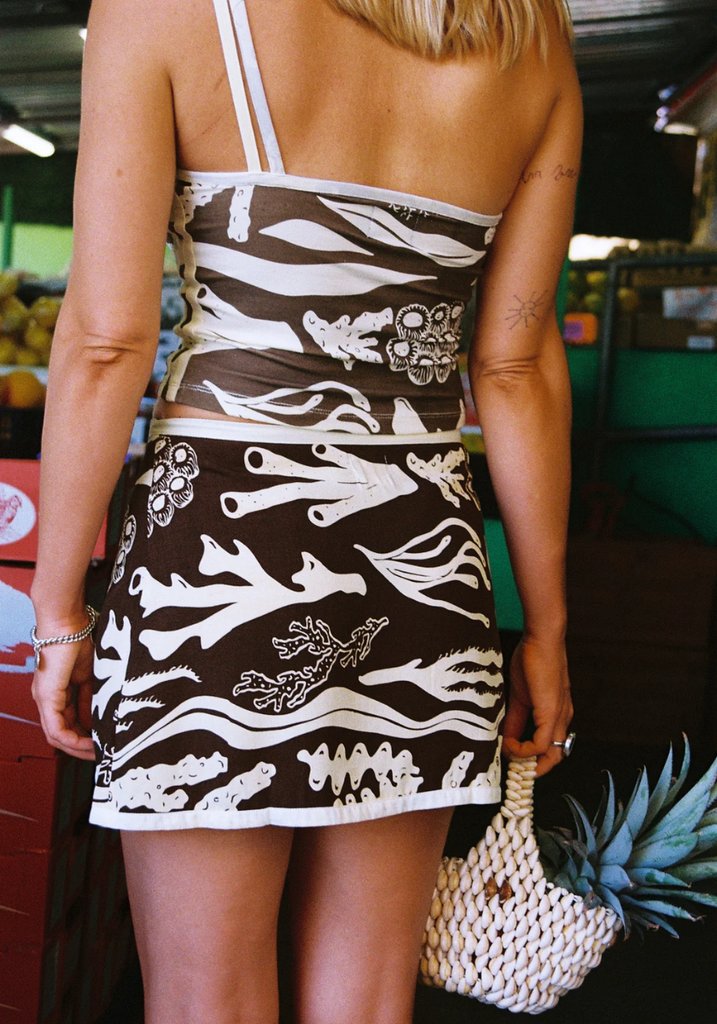Person wearing a brown and white patterned dress with a blurred background
