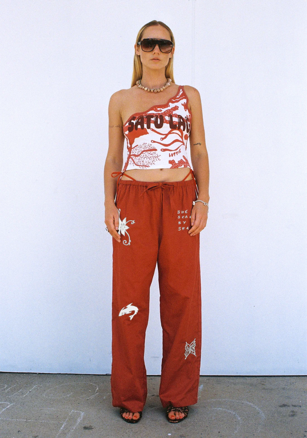 Person wearing a red tank top with graphic design and matching pants against a white background