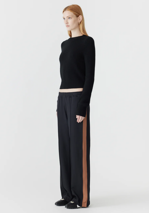 Person wearing a black outfit with a side stripe on a white background